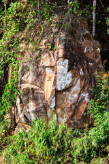 Stone face of Buddha by the Picturesque road in mountains of National park Bokor leading to Abandoned hotel Bokor Palace in Ghost town Hill station near Kampot. Cambodia