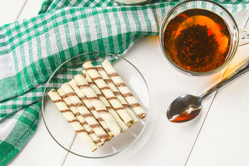 Striped wafer rolls, delicious chocolate snack on white wooden table.