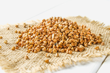 Raw buckwheat on a sack on a wooden table. Healthy diet food.