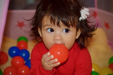 Fototapeta na wymiar Baby little girl holding ball up to mouth