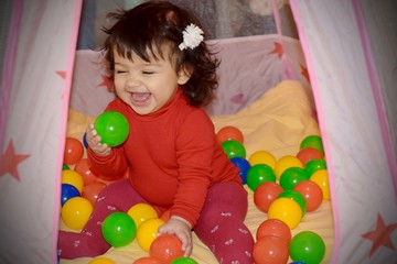 Fototapeta na wymiar Happy little girl smiling and playing with balls 