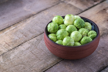 Brussels sprouts in ceramic bowl on rustic wooden table.