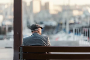 Fotobehang Hombre adulto irreconocible sentado en un banco frente al puerto © Bujia