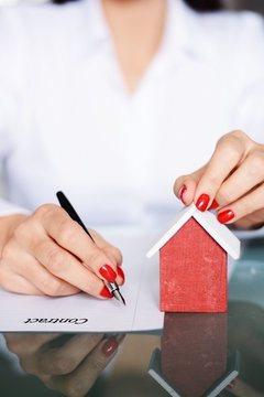 Woman signing a contract when buying a new house with mortgage loan, portrait image