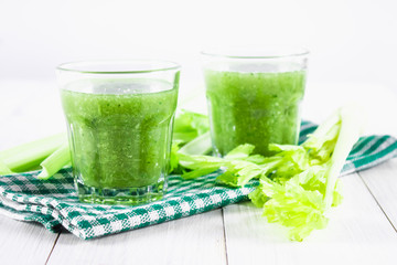 Vegetable cocktail made from celery leaves, healthy lifestyle on a white wooden background.