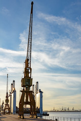 Cranes and others cargo equipments in front of the sea during sunset on the harbor pier