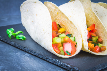 Traditional Mexican tacos with meat and vegetables on wooden background.