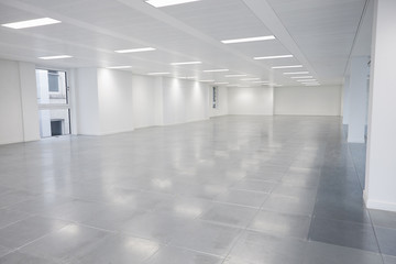 Fototapeta premium Vacant open plan office space with lights on
