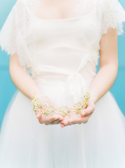 brides hands holding golden headpiece