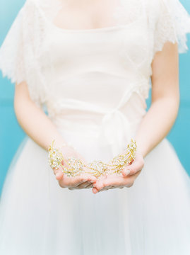 brides hands holding golden headpiece