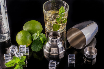 Alcoholic drink with lime mint and ice cubes on a dark background