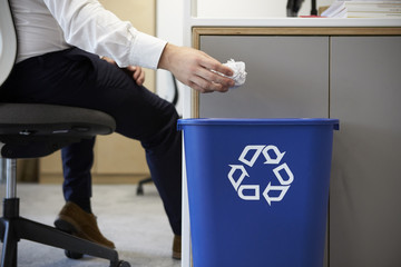 Man dropping screwed up paper into recycling bin, close up