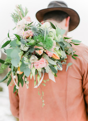 pastel coloured bouquet on back of groom