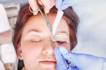 Surgeon applies a bandage to the female patient's eyelids after a blepharoplasty operation