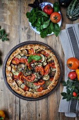 On a wooden table on a plate of vegetable gallet from tomatoes, eggplant, courgettes and bell peppers. Style Rustic