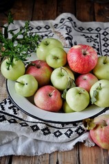 Naklejka na ściany i meble On a wooden table on a cotton towel a metal dish with fresh red and green apples