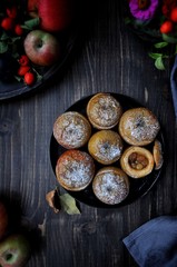 On a wooden table, a dish with baked sweet apples stuffed with raisins and sprinkled with powdered sugar. View from above