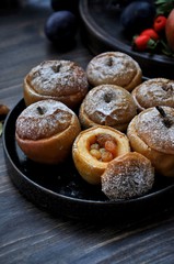 On a wooden table, a dish with baked sweet apples stuffed with raisins and sprinkled with powdered sugar. Closeup