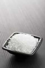 natural salt into black bowl on wooden table