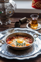 Copper pan with fried eggs and sausages, turkish style