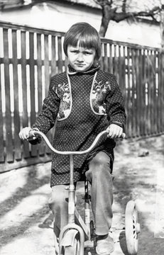 Vintage photo of little girl on old bicycle