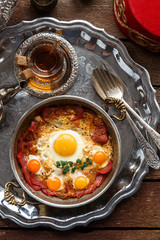 Turkish cured beef and fried eggs in copper pan, traditional breakfast, top view