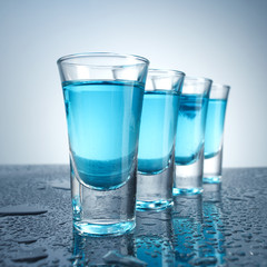 Vodka glass with ice on blue background