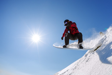 Fototapeta na wymiar Snowboarder jumping from the springboard against the sky