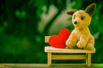 red heart and dog doll on the wooden bench with dramatic tone