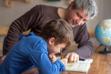 Young little shoolboy solving mathematics homework with father