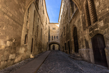Fototapeta na wymiar Cobblestone street between high walls in a medieval city