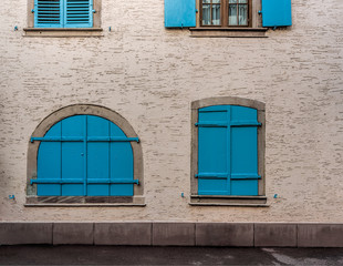 Fototapeta na wymiar Blue windows on pale yellow walls of a small town