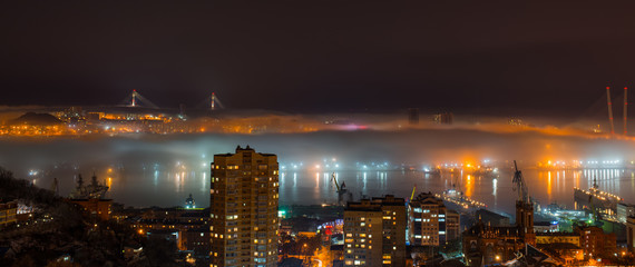 Vladivostok cityscape night view. Fog over the city.