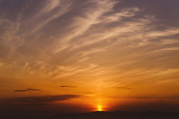 Fototapeta na wymiar Dramatic sunset sky with orange colored clouds and sun.