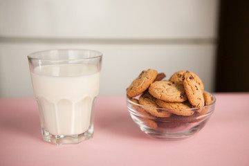 Glass of milk and chocolate chip cookies on the pink table