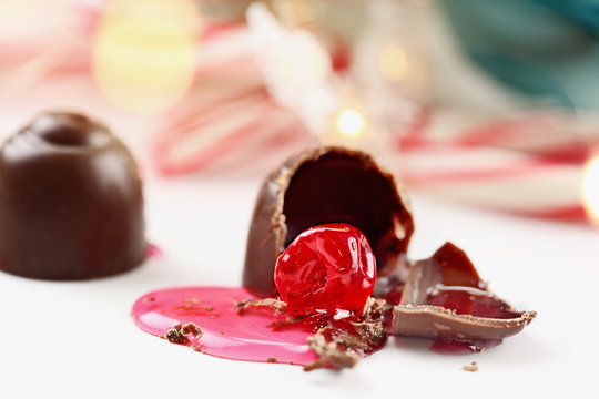 Chocolate covered cherries. Shallow depth of field with selective focus on bitten portion of candy truffle with exposed cherry.
