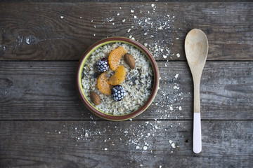 Dish with oatmeal and fruit and spoon on the wooden table 