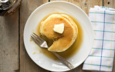 Homemade little. pancakes on the white plate on the wooden table, top view