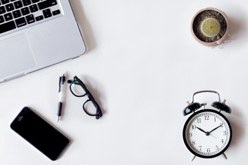 White office desk table with laptop, cactus, smartphone, and glass. Top view with copy space, flat lay.