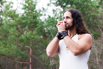 Young man playing the harmonica in a forest glade.