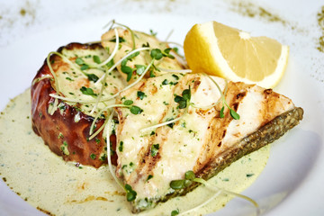 baked fish in oil with sauce and lemon