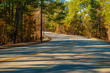 The turn of the Robert E Lee Boulevard with long shadows of trees in the Stone Mountain Park in sunny autumn day, Georgia, USA
