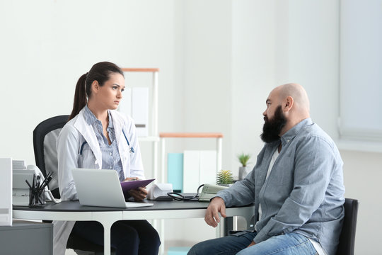 Young Female Doctor Consulting Overweight Man In Clinic