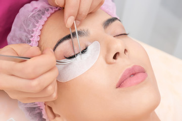 Obraz na płótnie Canvas Young woman undergoing eyelash extensions procedure, closeup