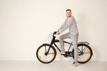 Fototapeta premium Handsome young hipster man with bicycle near light wall