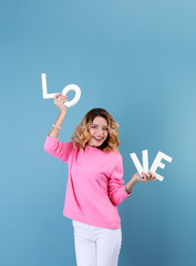Attractive young woman with word LOVE on color background
