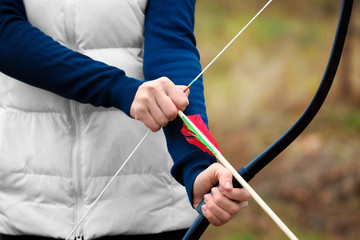 Woman practicing archery outdoors, closeup