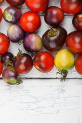 Different tomatoes on the white wooden background