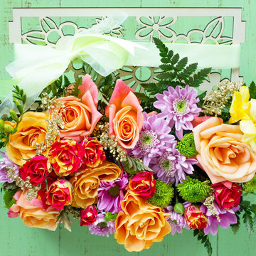 Background Valentine's Day or wedding. Basket bouquet of roses and chrysanthemums on a vintage wooden background. Flat lay. Top view with copy space.