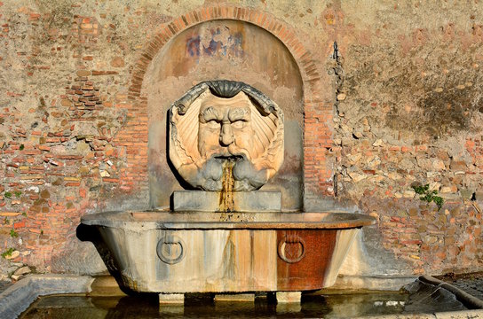 Beautiful fountain in orange gardens in Rome, Italy. Is this wonderful fountain of a giant, grotesque mask, which spits water into a giant, ancient Roman basil.